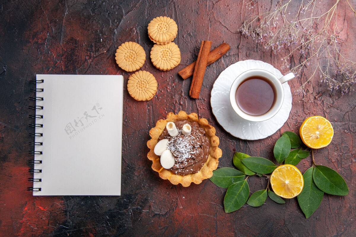 甜点顶视图一杯茶 黑桌子上有小蛋糕和饼干甜点饼干蛋糕记事本咖啡