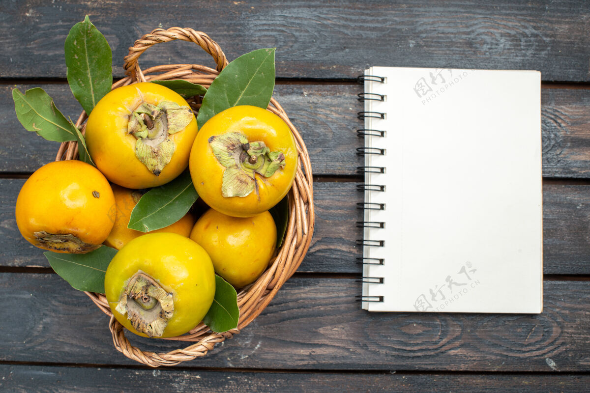 新鲜的柿子顶视图新鲜柿子放在木桌上的篮子里 水果醇香熟透食物笔记本笔记
