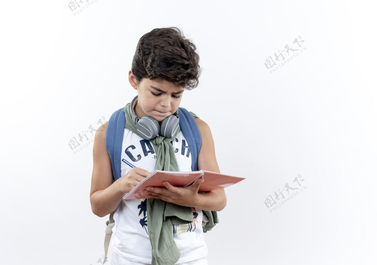 背想着那个背着书包 戴着耳机的小男孩在白色的笔记本上写着什么写作手势白色