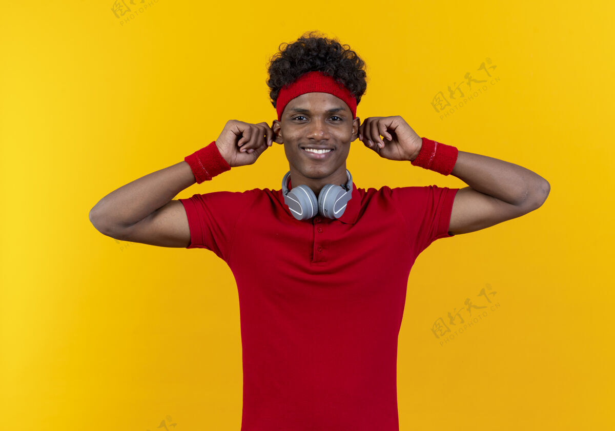 大带着头带和腕带的微笑的年轻运动型男人黄色运动头带