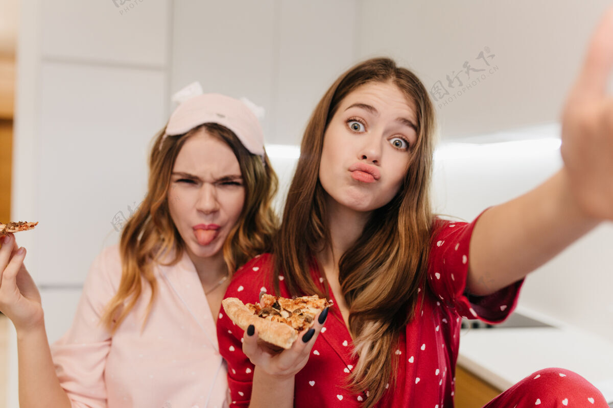 披萨可爱的年轻女子吃比萨饼 到处闲逛积极的姐妹们玩得开心 享受最喜欢的快餐娱乐小吃美味