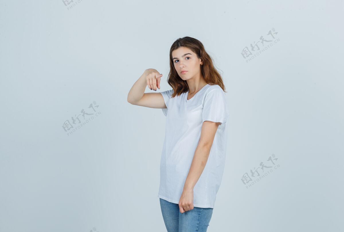 肖像穿着白色t恤的年轻女孩指着镜头 看上去很懂事 正对着镜头漂亮休闲休闲