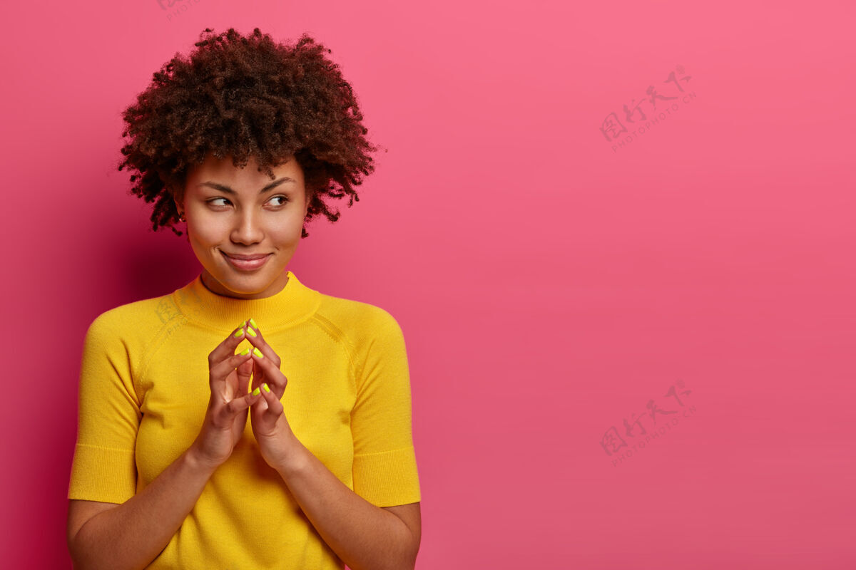 室内我的计划是完美的漂亮的非洲裔美国女人设计了一些东西 手指尖尖 表情狡黠地站在一边 狡猾地笑着 在粉色的墙上摆姿势 为你的宣传片留出空间学生狡猾女人