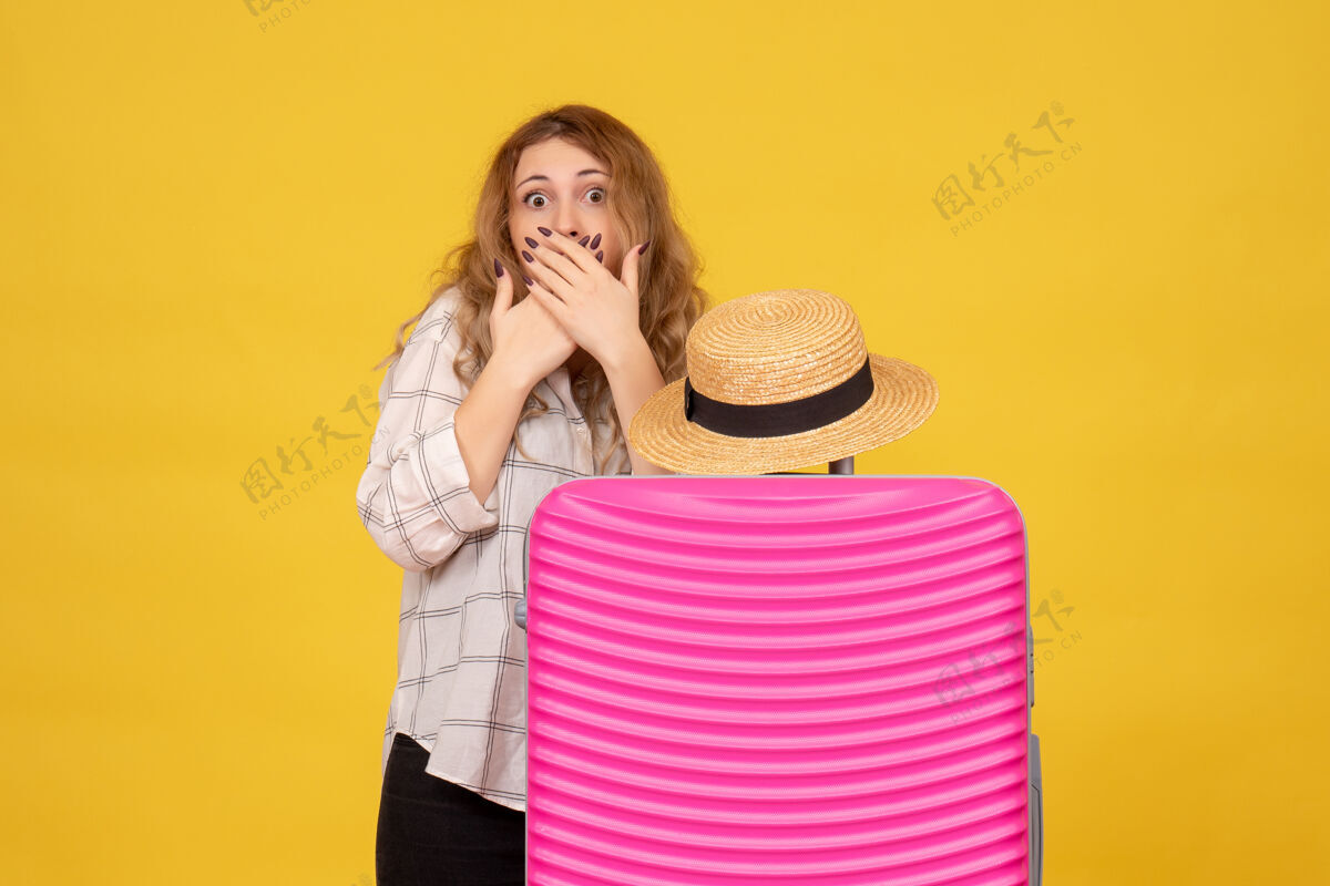 包站在粉色包后面惊讶的年轻女士的俯视图休闲人上衣