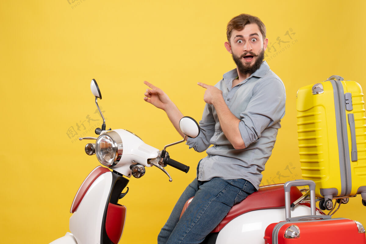 旅游旅游概念与年轻惊讶胡须男子坐在摩托车上指着它的黄色背面正面视图年轻人人传送带