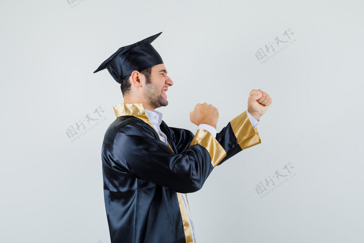 肖像一个年轻人穿着毕业制服展示获奖者的姿态 看上去很幸运男人聪明休闲