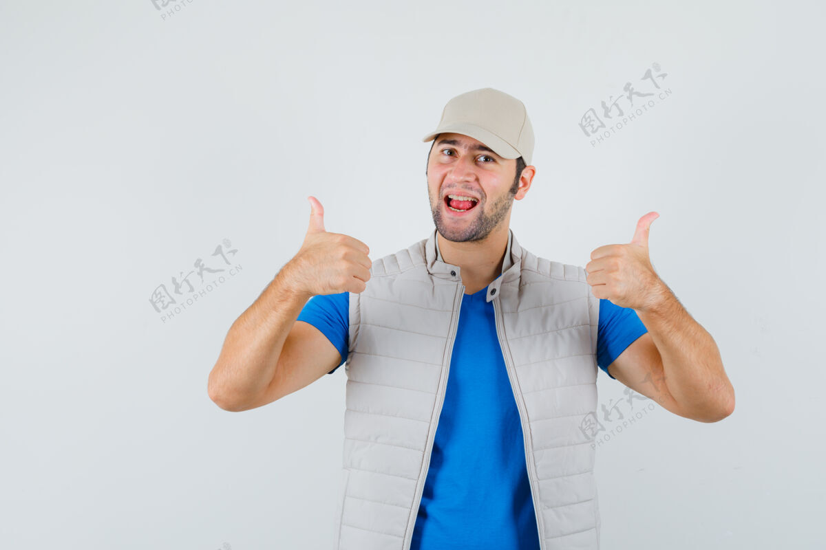 成功年轻人在t恤衫 夹克衫 帽子上竖起大拇指 看起来很开心正面图衬衫帅哥站立
