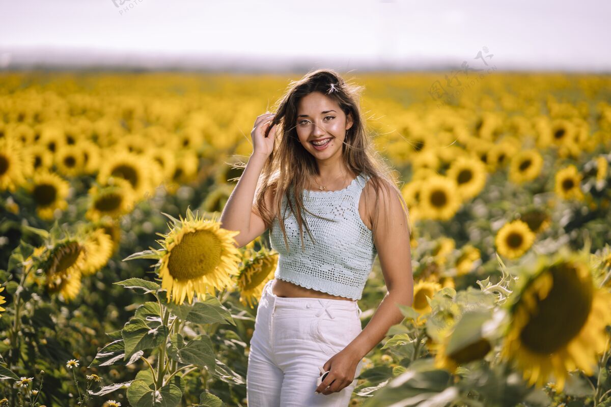 美丽在阳光明媚的日子里 一位白人年轻女性在向日葵的田野里摆姿势的水平镜头明亮可爱开花