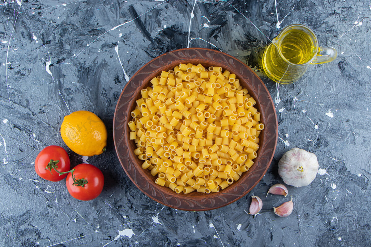 黄一堆生的移液管把意大利面和新鲜的红色西红柿和油放在一个碗里意大利生未煮
