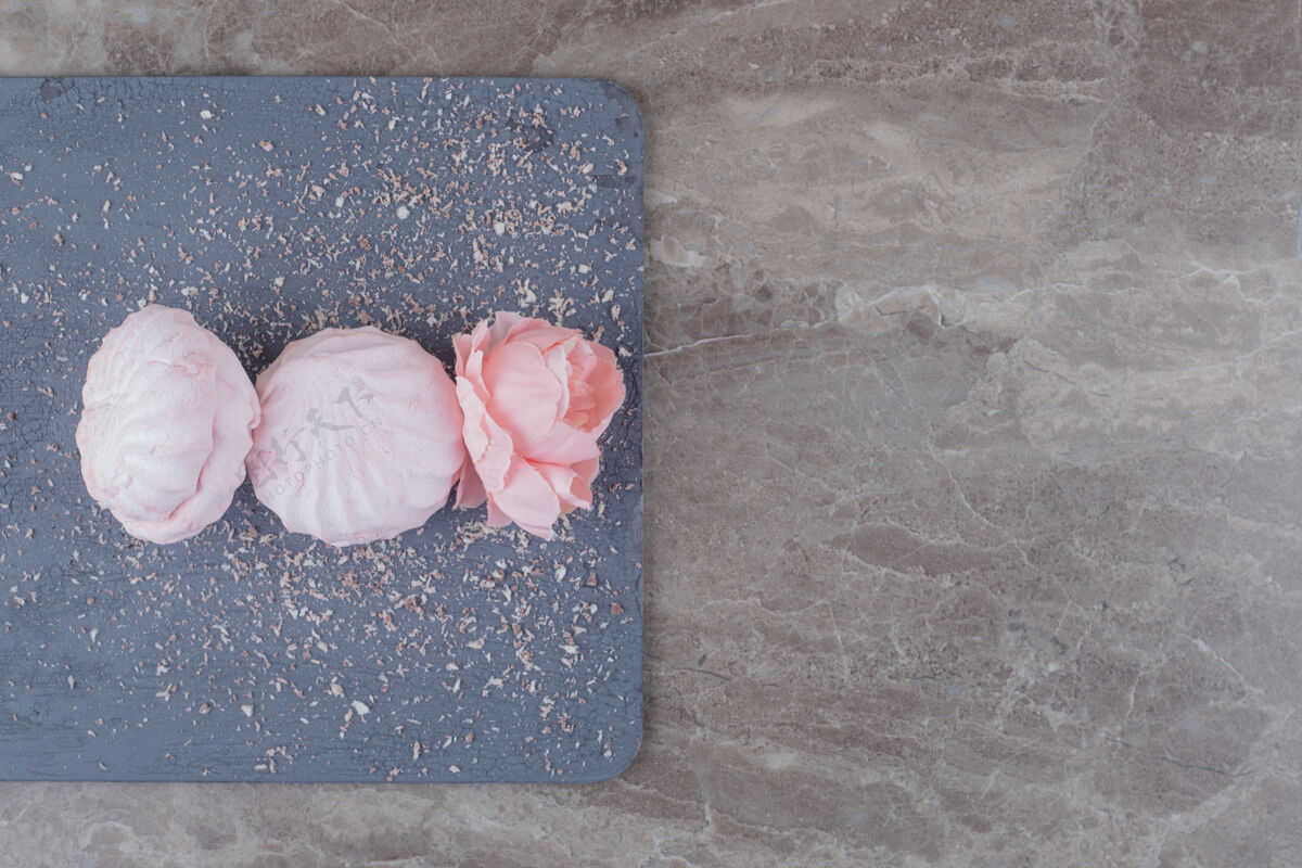 美味饼干和花冠放在大理石板上美味小吃鲜花