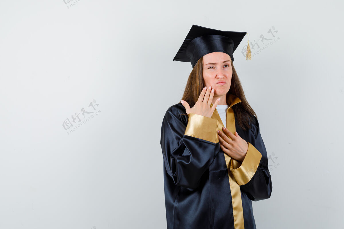 女年轻的女毕业生手放在脸颊上 手放在胸前手完美人