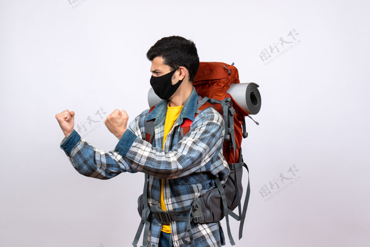 时尚正面图愤怒的年轻徒步旅行者背着背包和面具准备战斗背包设备建筑