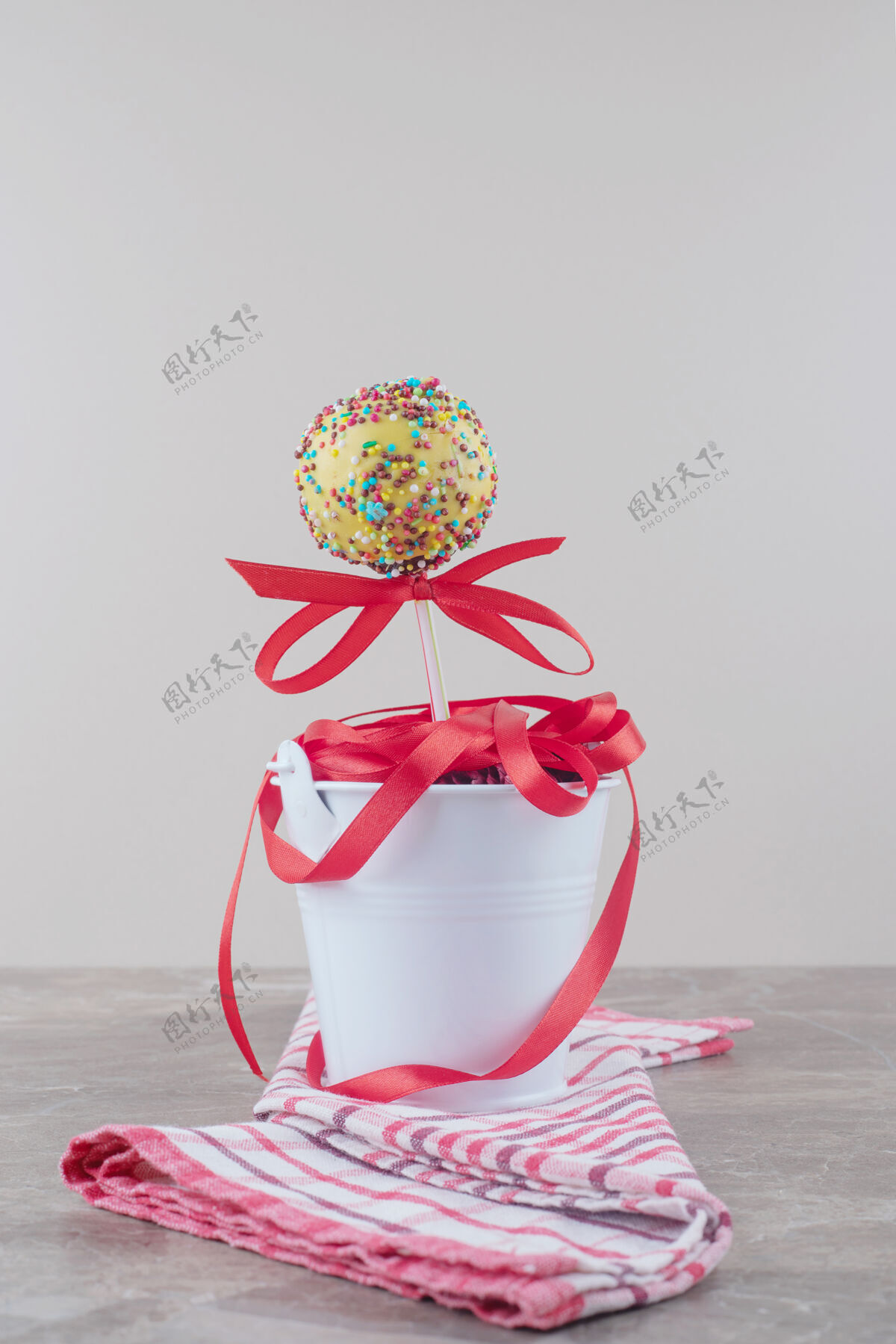 糕点一捆丝带和一个棒棒糖放在大理石上的毛巾桶里外套美味桶