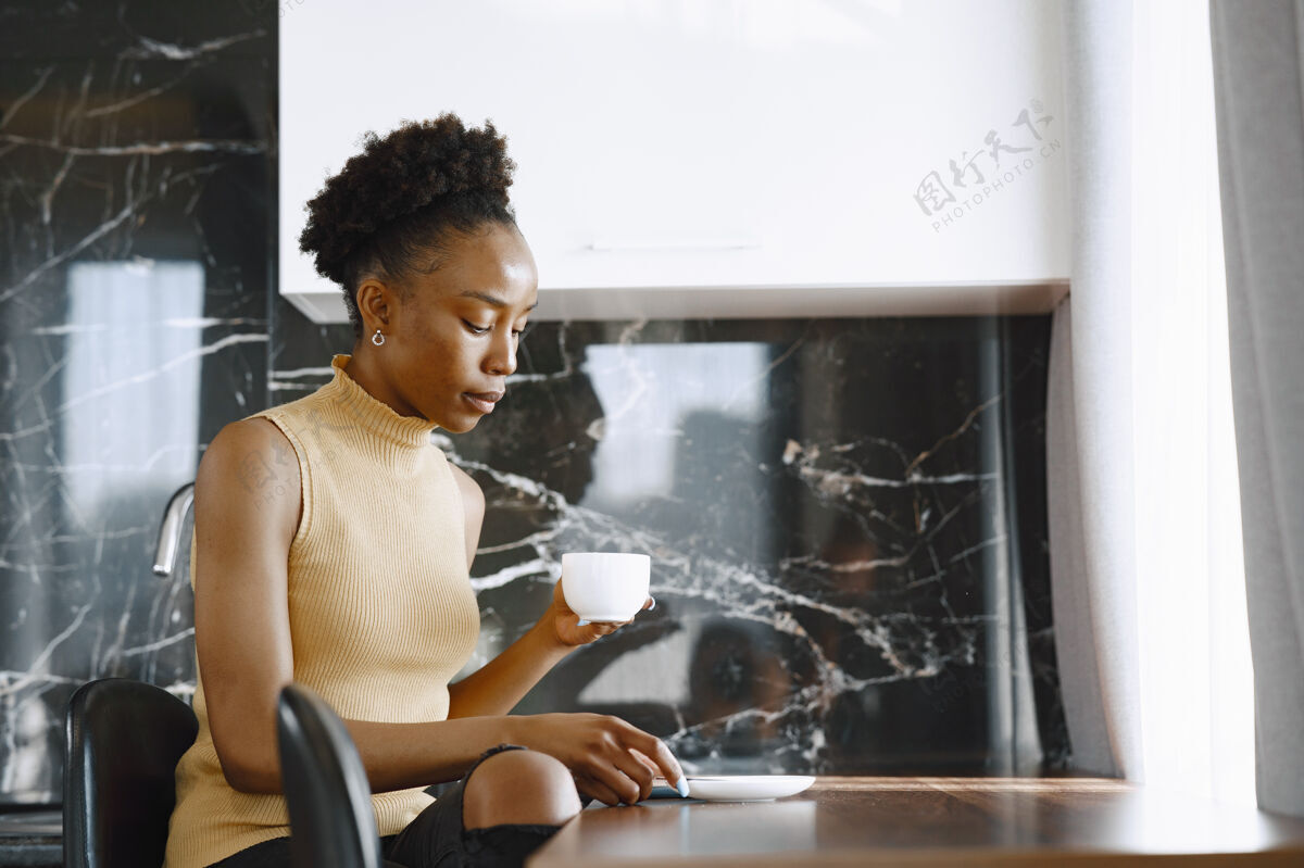女性坐在厨房里的女孩喝咖啡的女人靠窗的女人窗户肖像女孩