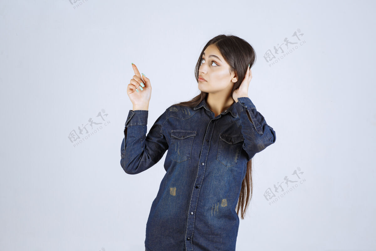 人类穿着牛仔衫的年轻女子举起双手 指着上面的东西年轻聪明女性