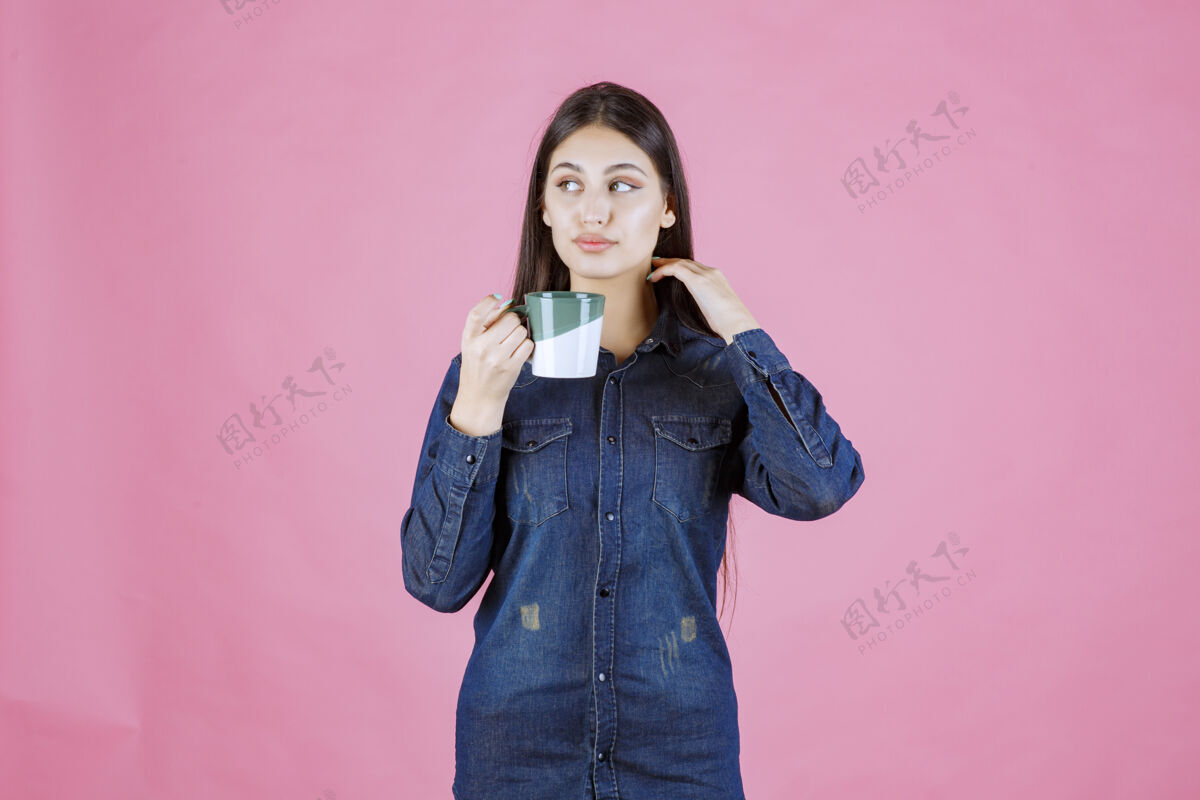 人类年轻女子拿着一个白绿色的咖啡杯 闻着姿势工人年轻