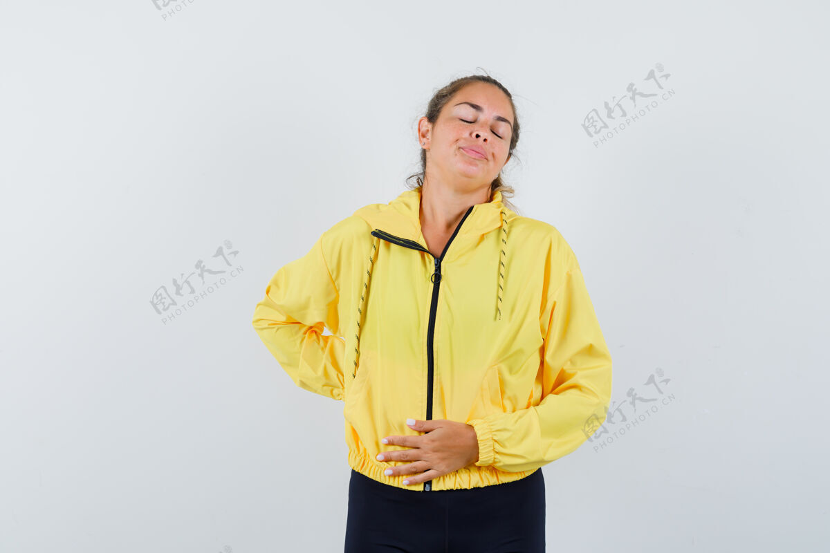 腹部一个金发女人 手放在肚子上 穿着黄色棒球服和黑色裤子肚子疼 看起来很疲惫筋疲力尽快乐女性