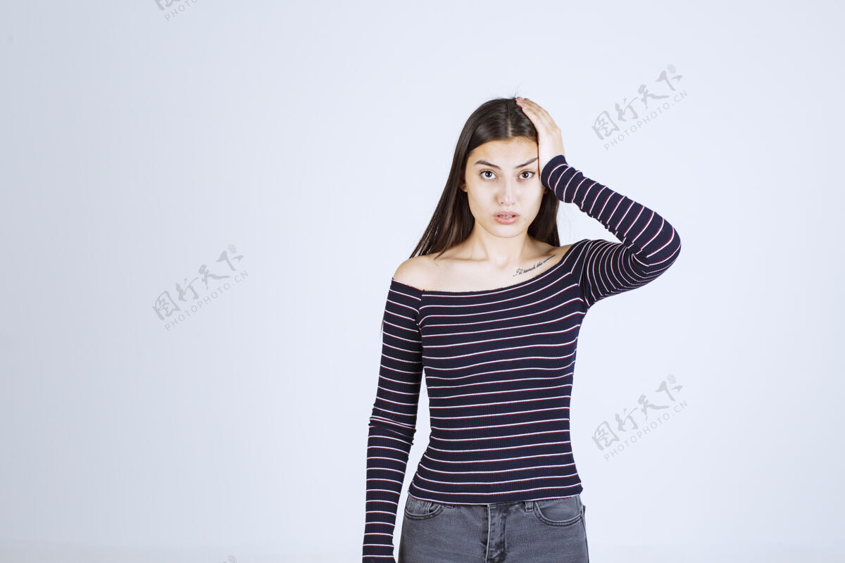 女人穿着条纹衬衫的女孩抱着她的头 因为她筋疲力尽或头痛成人生病无聊
