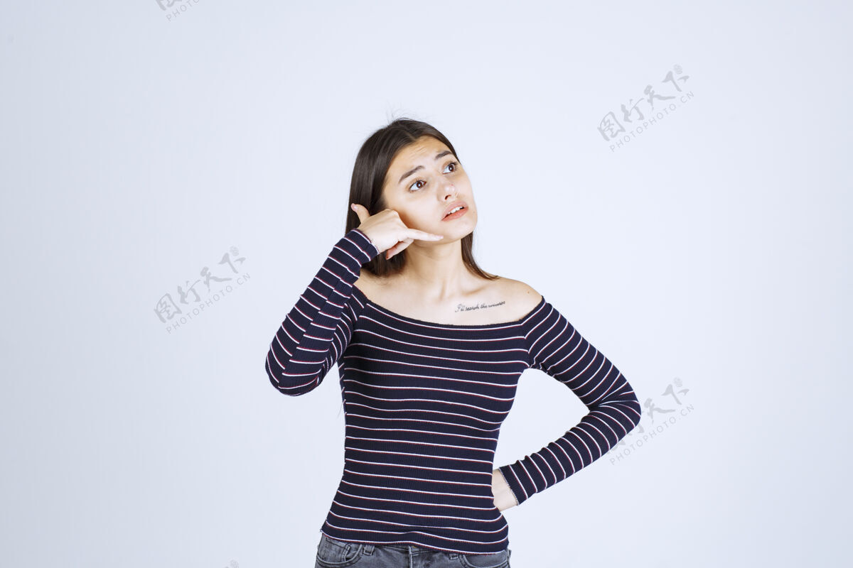 吸引力穿条纹衬衫的女孩显示呼号年轻工人姿势
