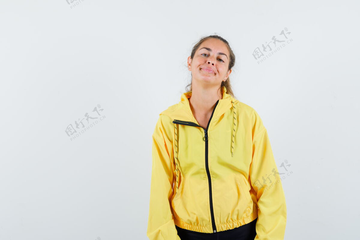 快乐年轻女子站直了 微笑着对着镜头摆姿势 穿着黄色棒球服和黑色裤子 看起来很可爱护理黑发自然