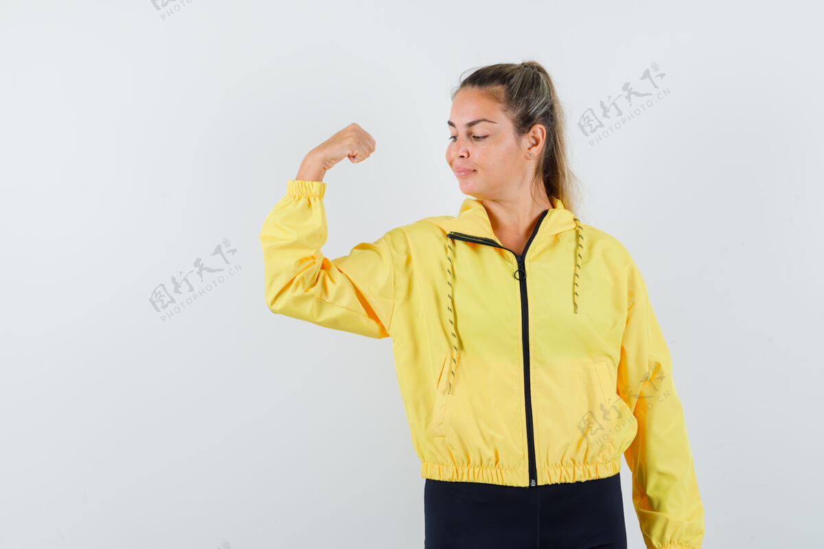干净穿着黄色棒球服和黑色裤子展示肌肉的年轻女子 看起来很可爱前面夹克人