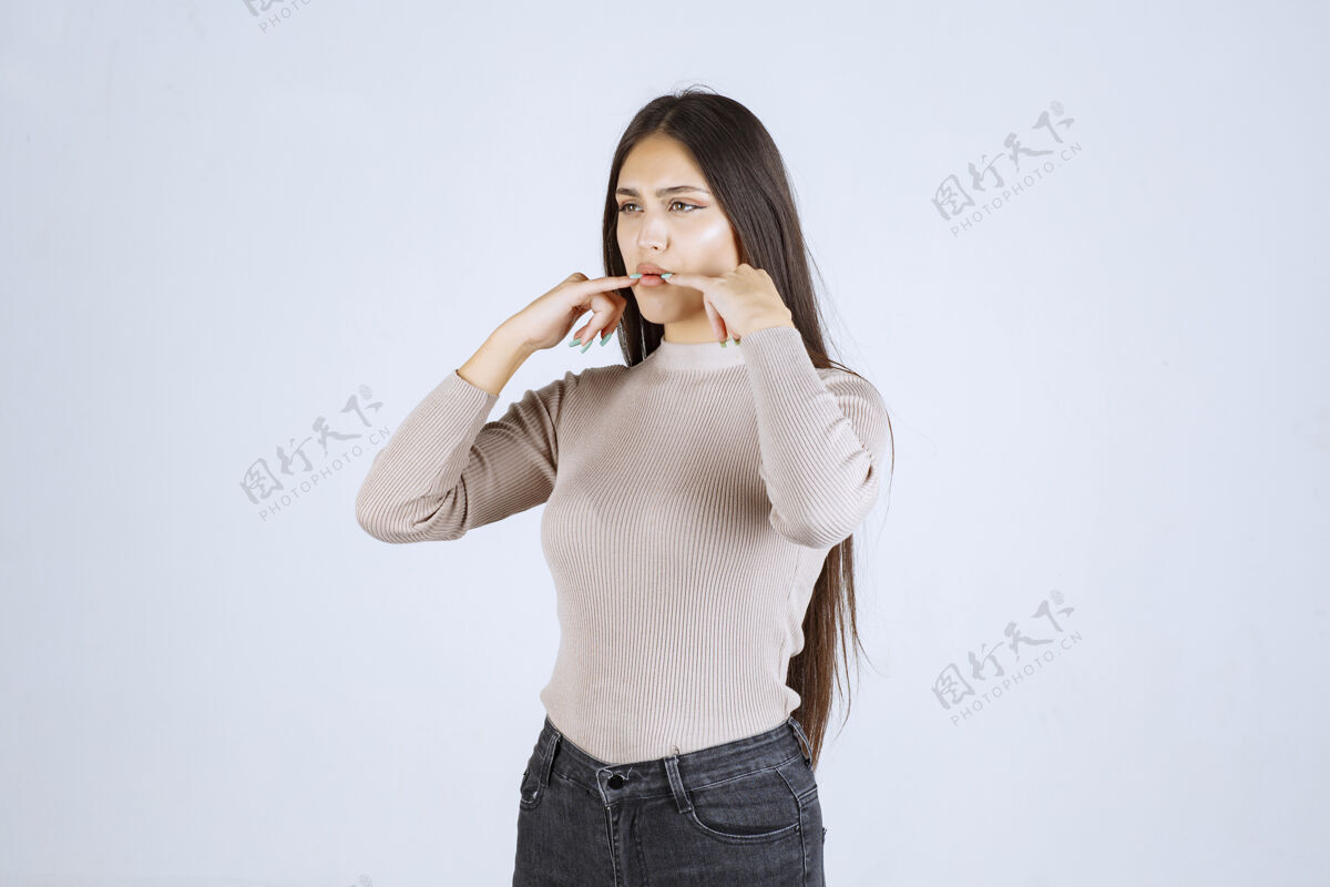 人体模特穿灰色毛衣的女孩用手指捂住嘴吹口哨休闲年轻工人