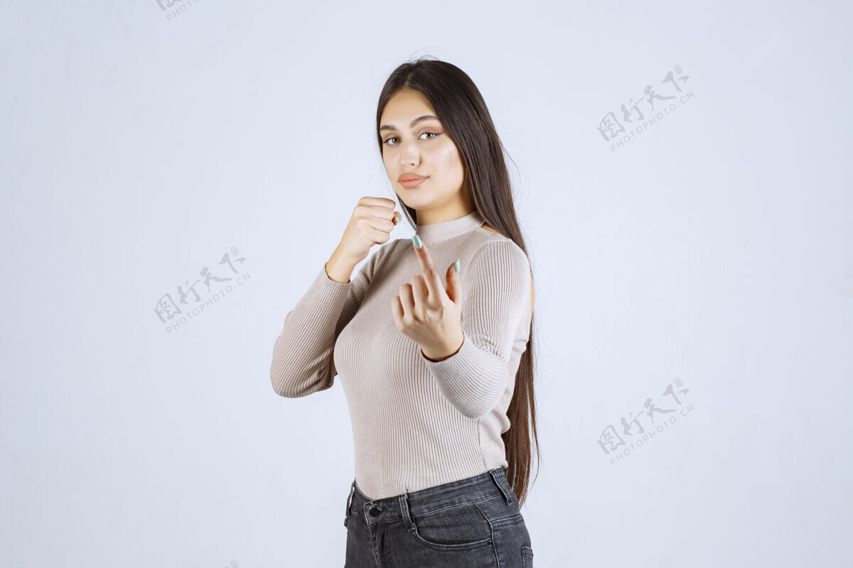 员工穿灰色毛衣的女孩展示她的拳头和力量服装人类人体模特