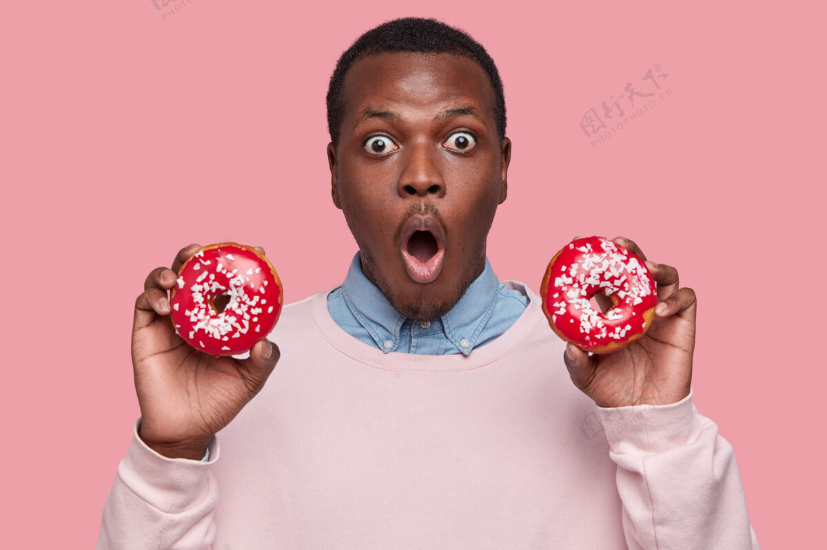 男性年轻的非洲裔美国人拿着美味的甜甜圈成年人洒男人