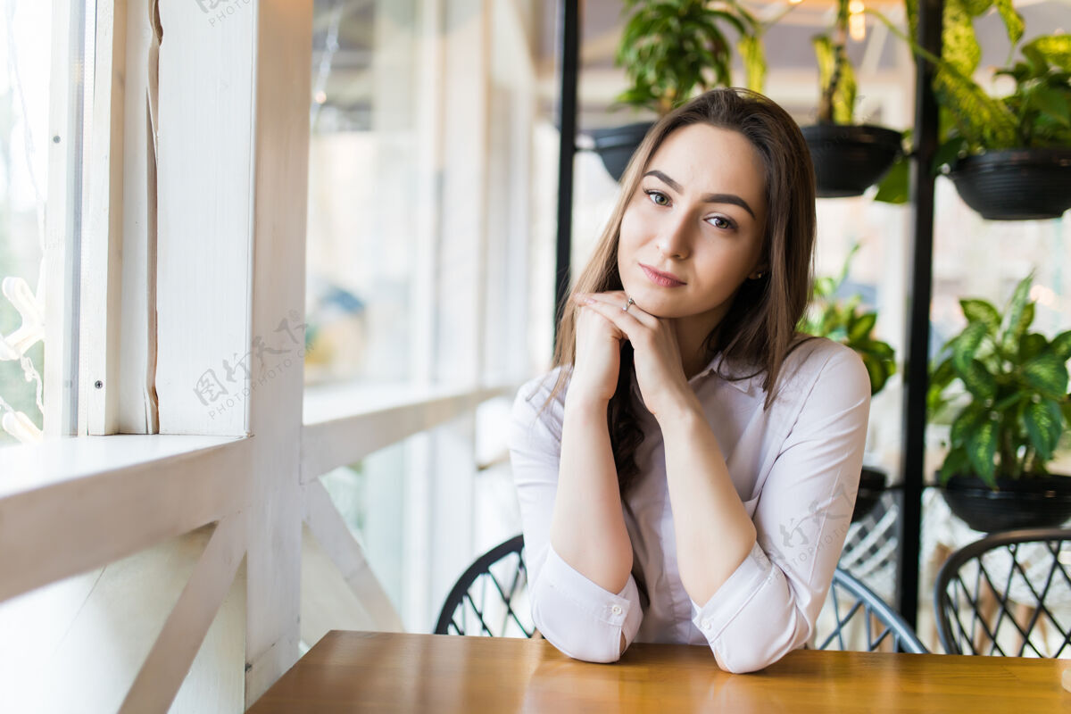模型快乐的年轻女子坐在咖啡馆里等着点菜微笑人互联网