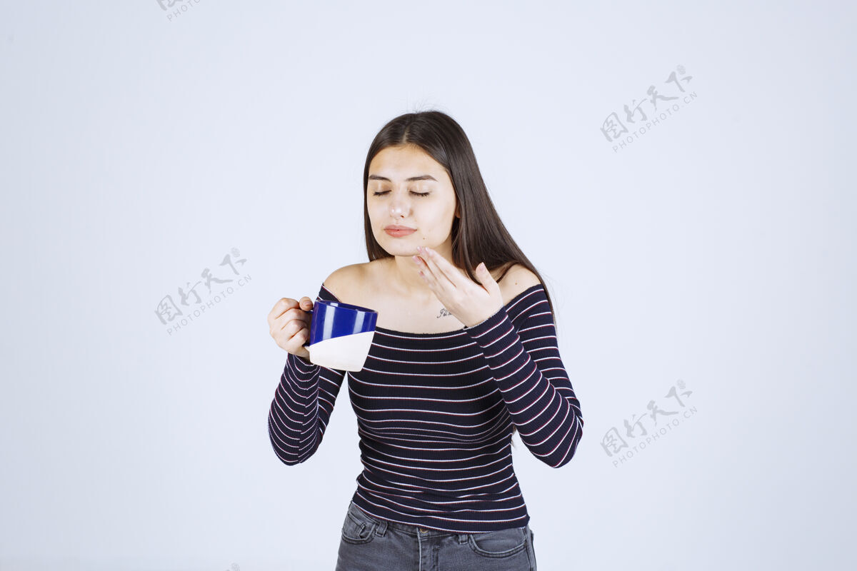美食家穿着条纹衬衫的女孩拿着一个咖啡杯 闻着咖啡味人类年轻人女人