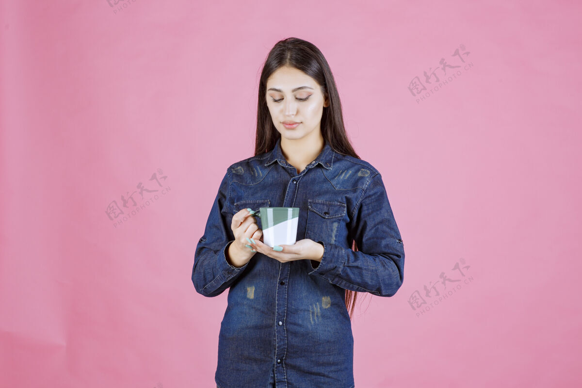 姿势年轻女子拿着一个白绿色的咖啡杯 闻着热模特成人