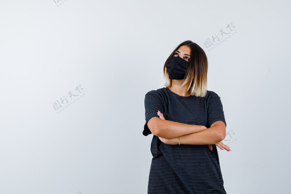 面具身穿黑色连衣裙 戴着医用面罩 双臂交叉站立的女士 看上去充满希望正视图头发模特漂亮