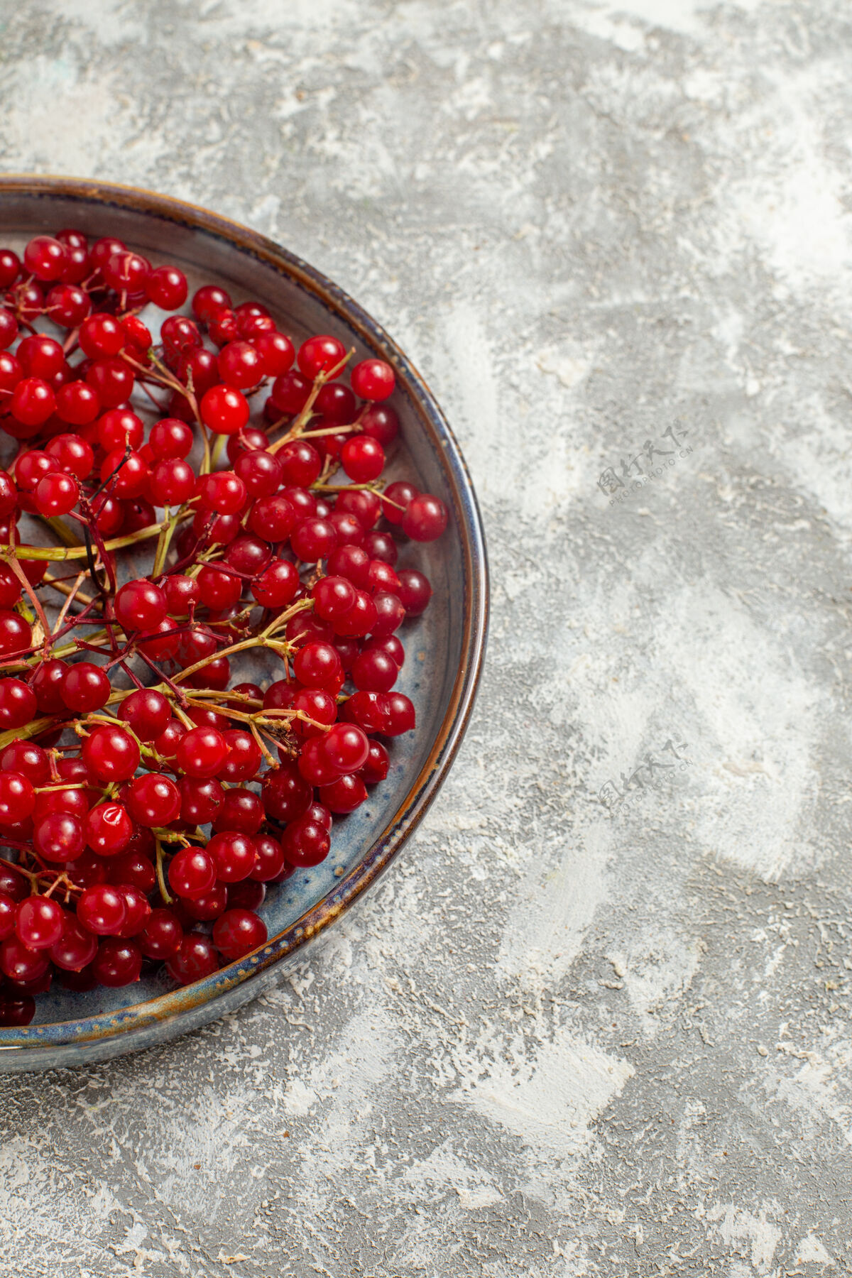 可食用水果正面图新鲜的红色小红莓放在白色桌上的托盘里 浆果的颜色是野红色红葡萄干葡萄干灌木