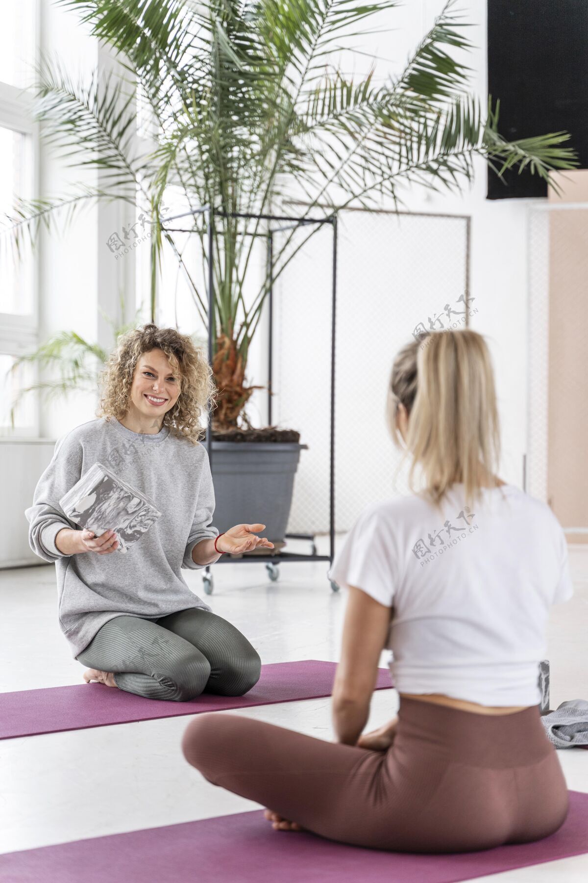 成人瑜伽课上坐在垫子上的全镜头女人训练女性运动