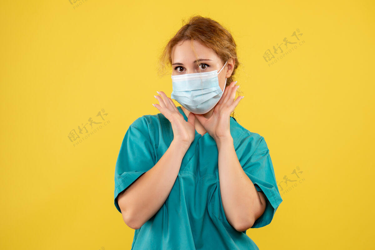 微笑黄墙上年轻女医生穿着医疗服 戴着口罩的正面图套装成人肖像