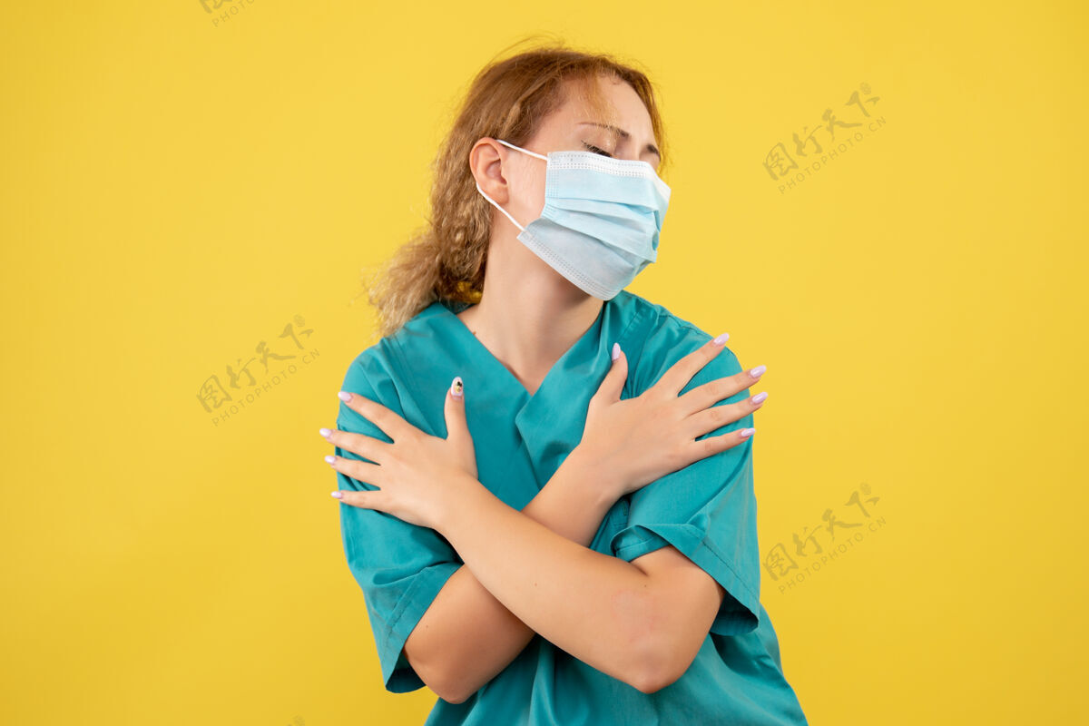 快乐黄墙上年轻女医生穿着医疗服 戴着口罩的正面图脸医学成人