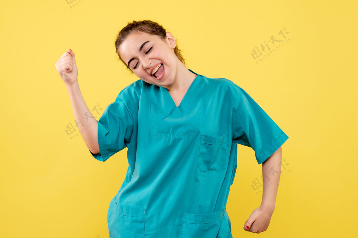 正面黄色墙上穿着医用衬衫的年轻女医生的正视图人医院成人