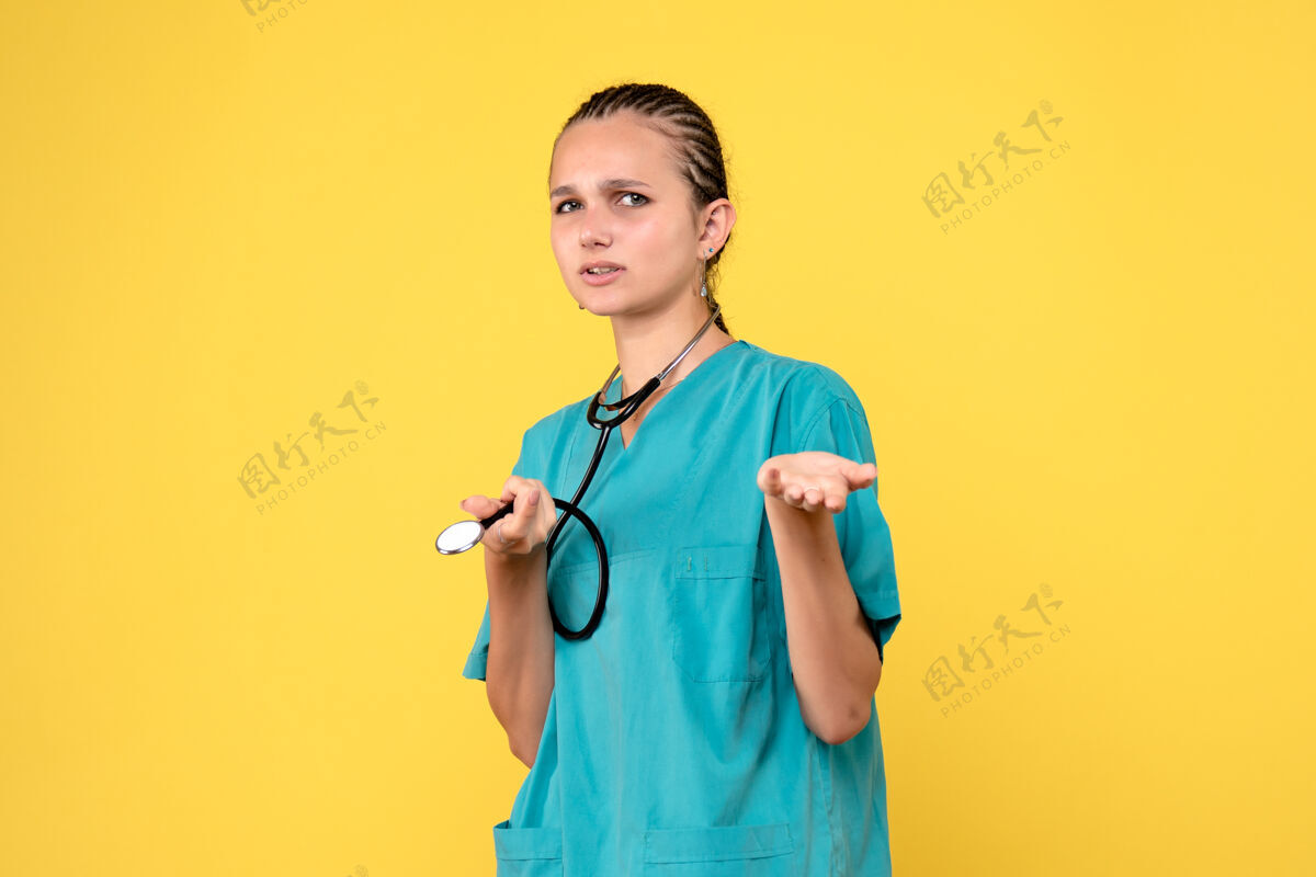 护士黄色墙壁上穿着带听诊器的医疗服的女医生的正视图医疗前面女医生