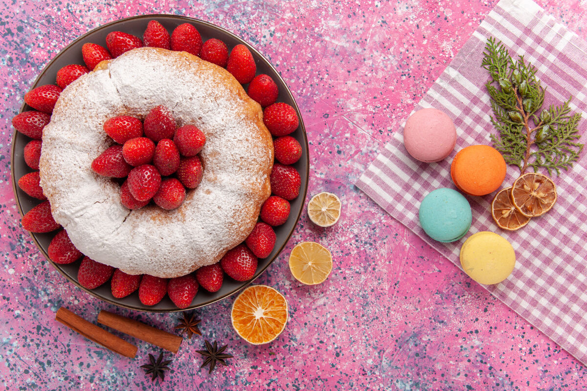 小吃顶视图糖粉派草莓蛋糕与法国马卡龙在粉红色饮食美味新鲜