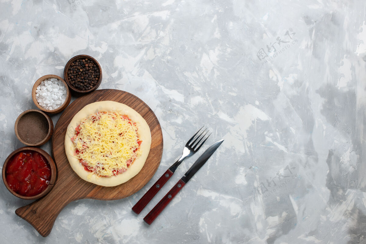 新鲜白色桌面上的生比萨饼 配奶酪和调味品烹饪健康丰富多彩