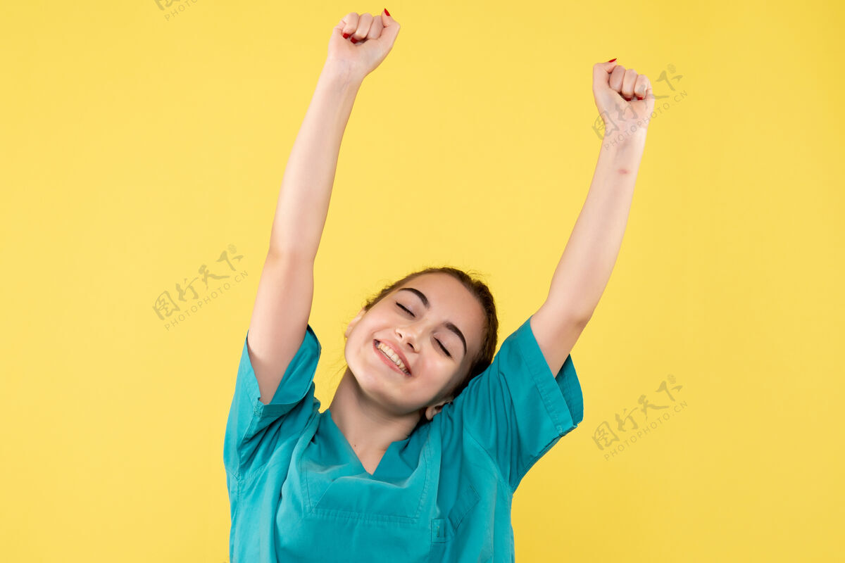 高兴身着医疗服的女医生在黄色墙上欢呼雀跃的正面图西装漂亮微笑