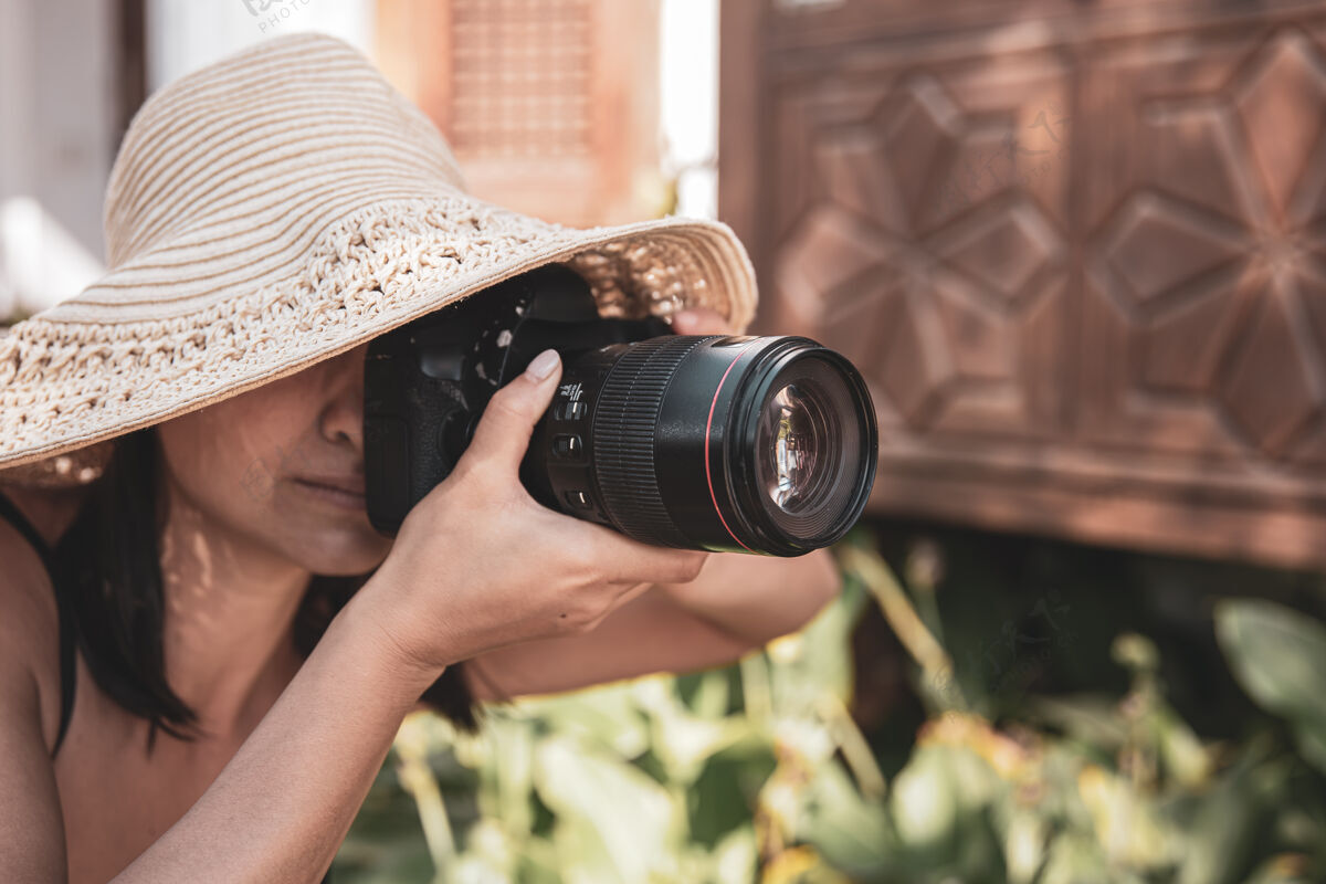 散步炎炎夏日 一位戴着帽子的年轻女子用专业单反相机拍照乡村休息专业