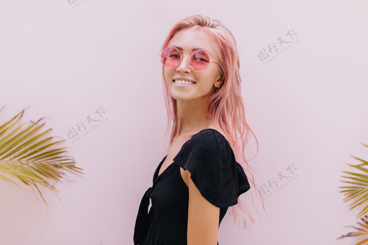 女人一个长着粉红色头发的女人站在工作室里奇异的棕榈树旁表情享受搞笑