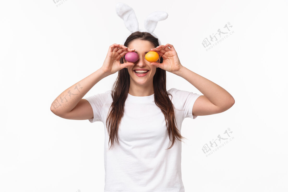 商业肖像富有表现力的年轻女子戴着兔子的耳朵和鼻子 手里拿着彩蛋人庆祝春天