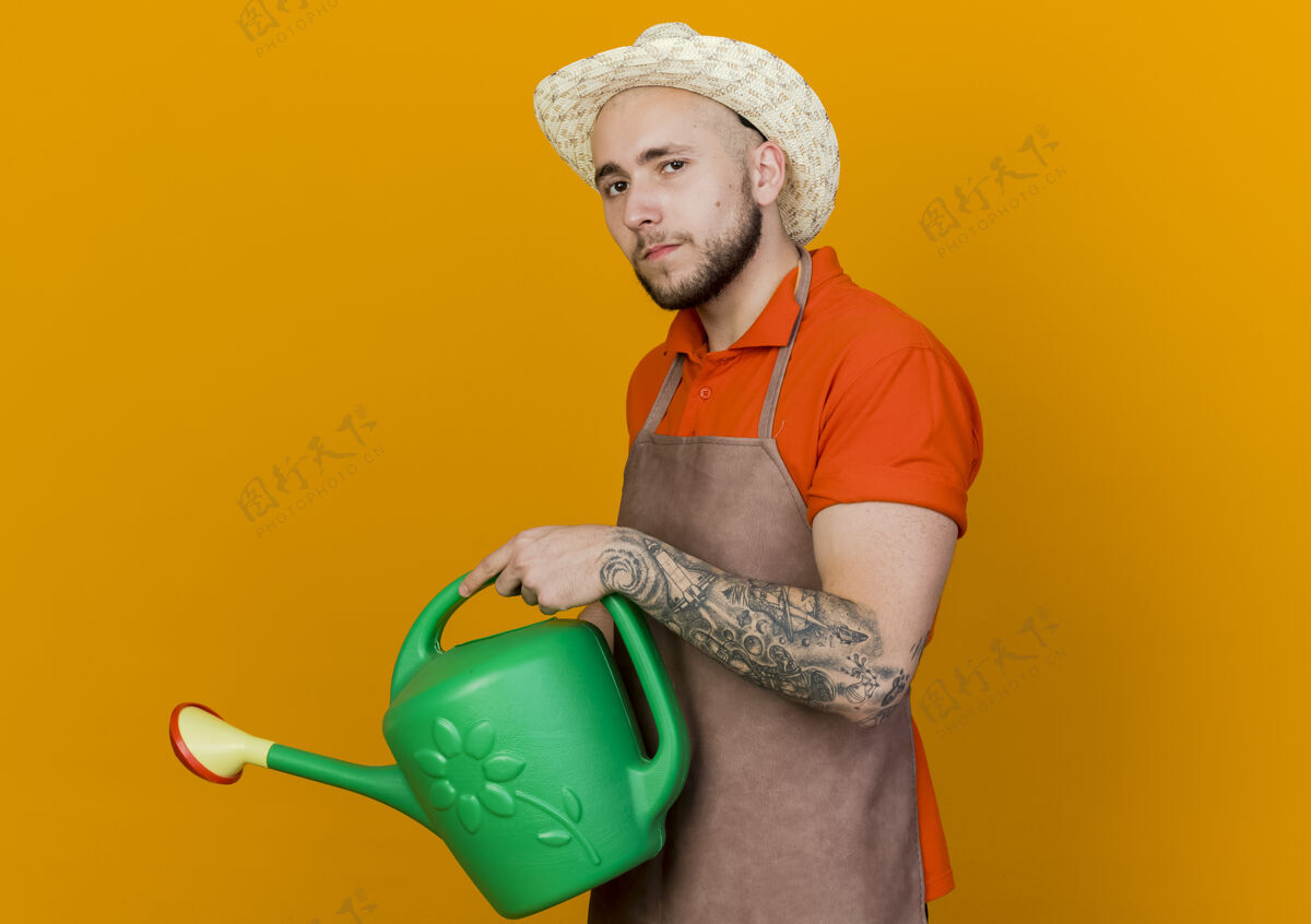 橙色自信的园丁戴着园艺帽拿着浇水罐浇水持有穿着