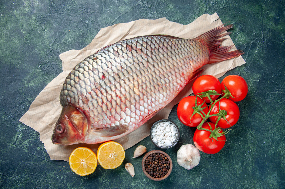 柠檬顶视图新鲜生鱼片与红色西红柿和柠檬片在深蓝色的背景餐海鲜健康