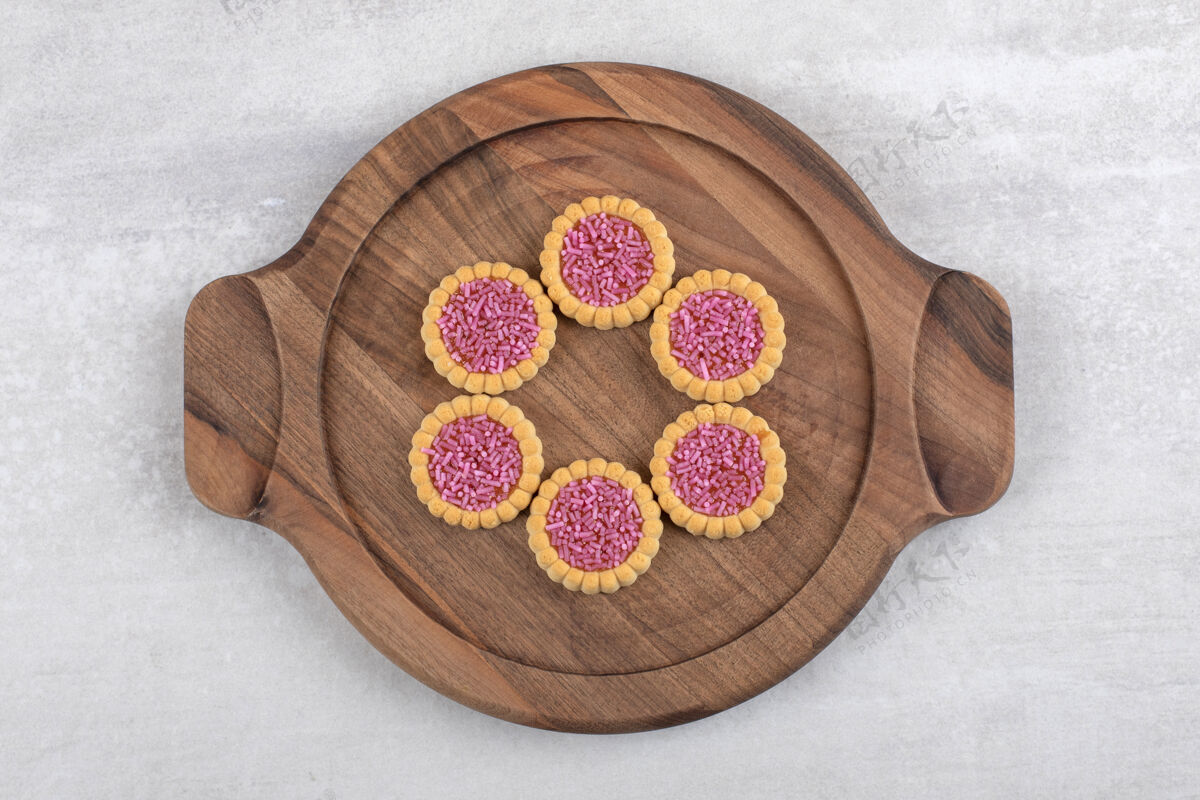小吃石头桌上放着一盘粉红色的甜饼点心面包房新鲜