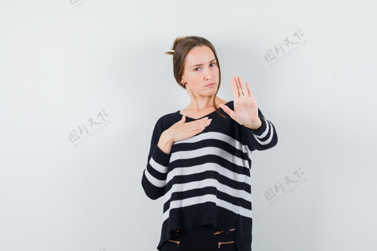 脸一位穿着休闲衬衫的年轻女士 摆出一副停下来的姿势 看上去很严肃前面人模型