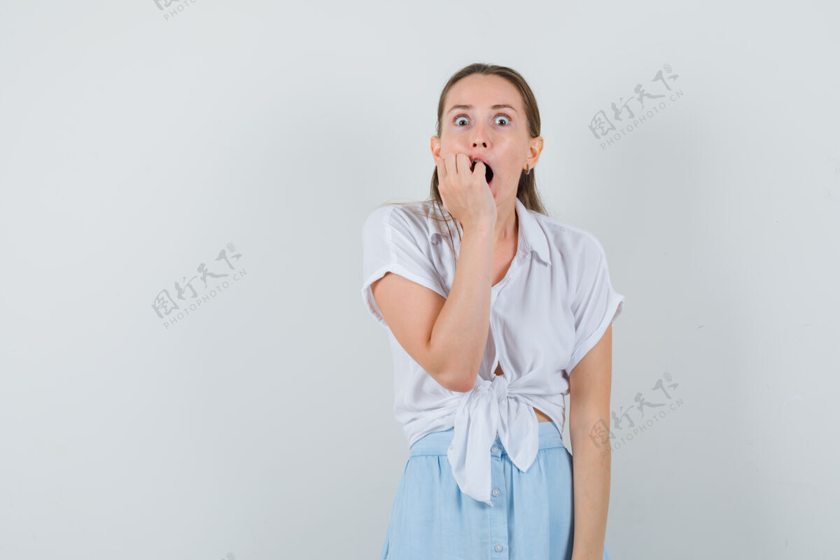 衬衫年轻的女士穿着衬衫 裙子 表情惊恐地咬着拳头自然裙子干净
