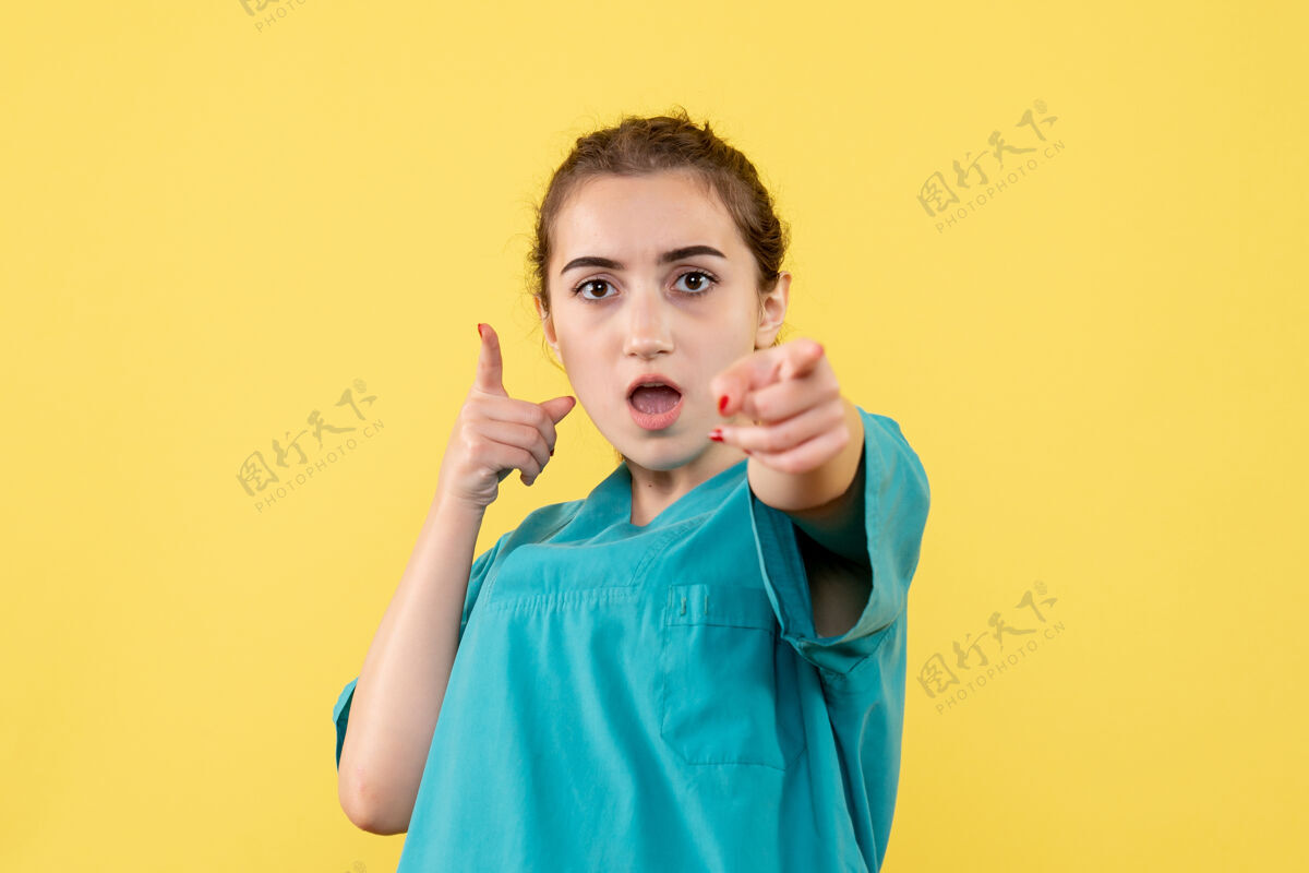 情绪黄墙上年轻女医生穿着医用衬衫的正面图快乐病毒微笑